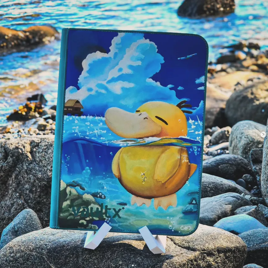 A hand-painted binder displayed on a stand beside coastal rocks and water